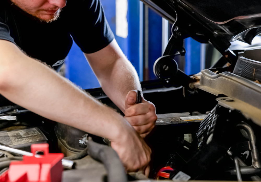 Service technician at Flow Nissan of Statesville working underneath the hood of a car