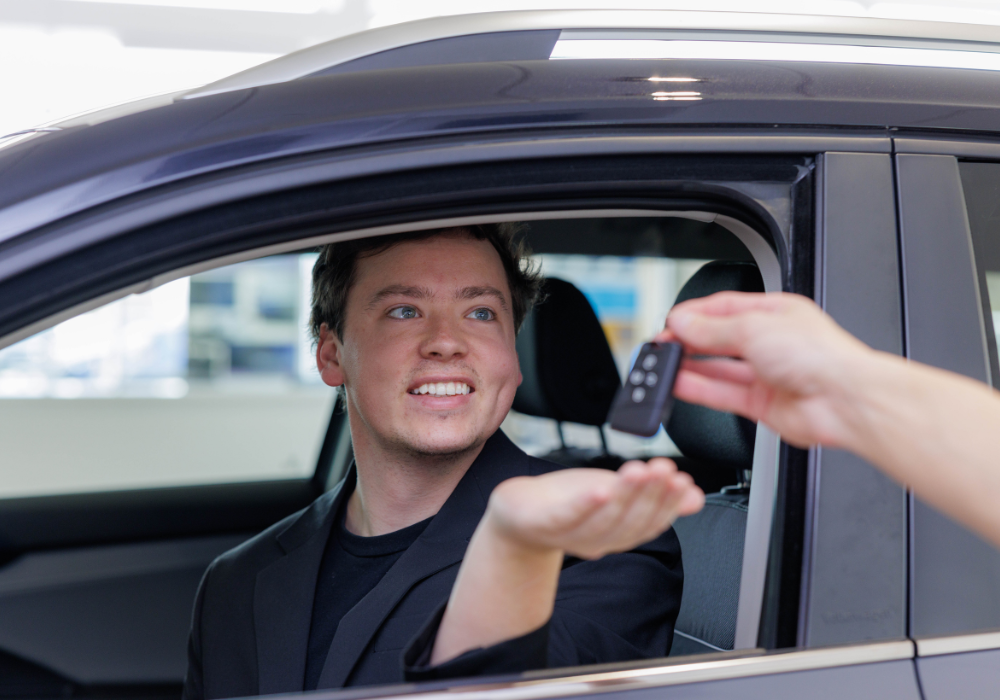 Customer being handed a set of car keys while sitting inside a car