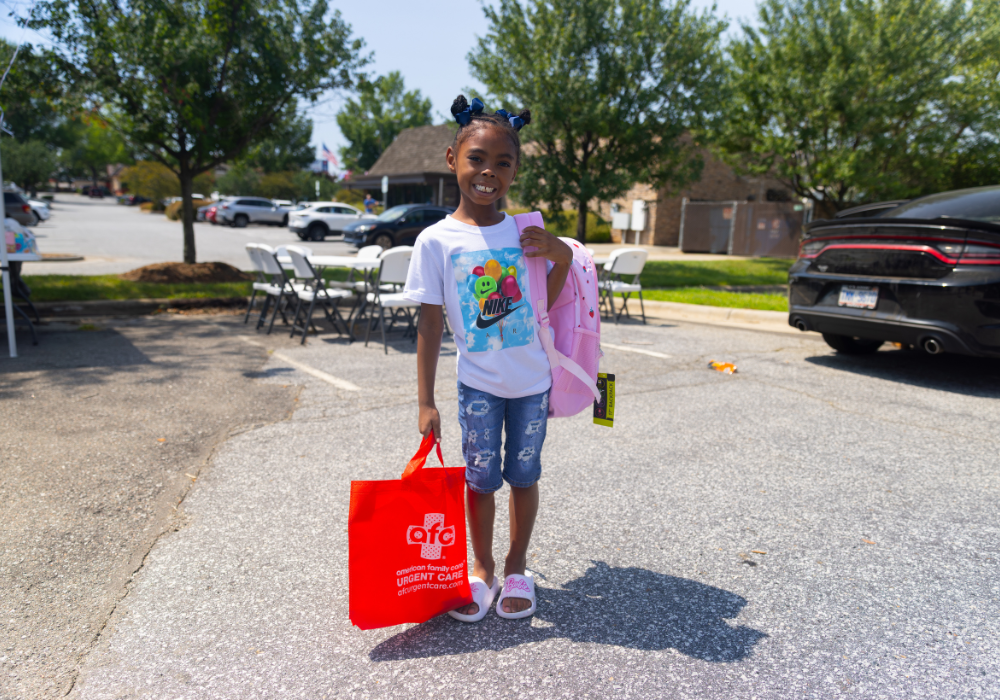 A child smiling and carrying a backpack