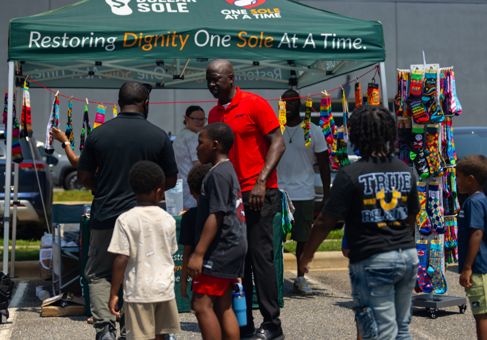 A group of people standing outside a test selling socks at Flow Nissan of Statesville.